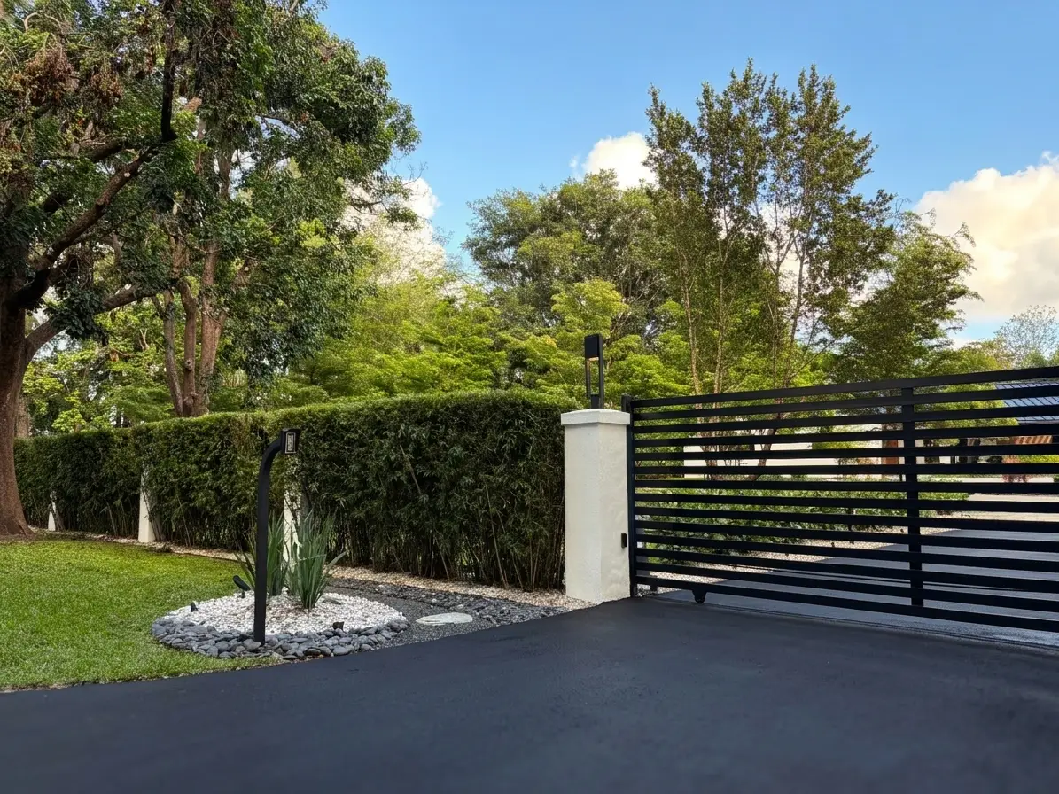 Outside west gate, black horizontal steel gate, white masonry pillar, bamboo hedge